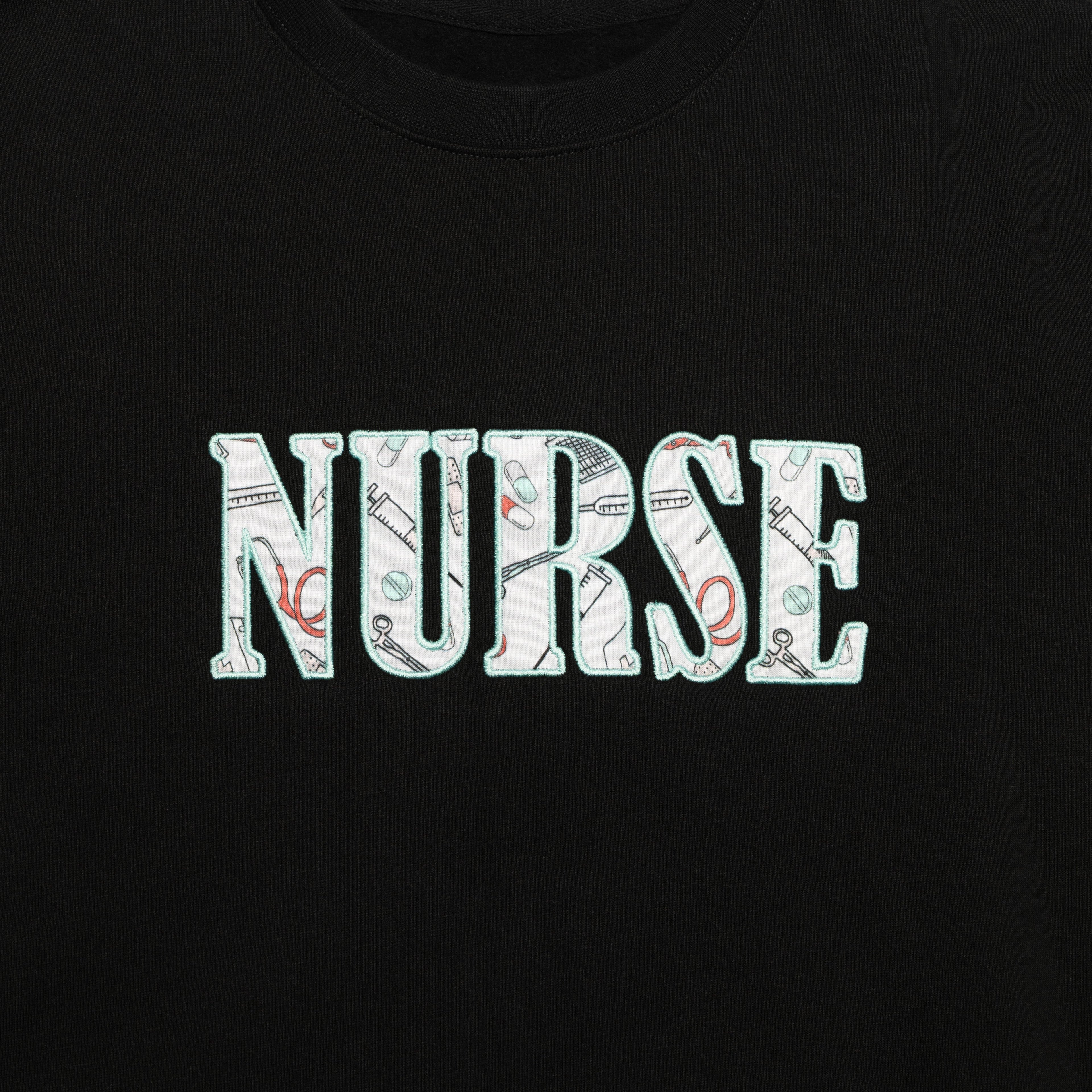 Close-up of the Nurse design appliqued on the chest of the Black crewneck