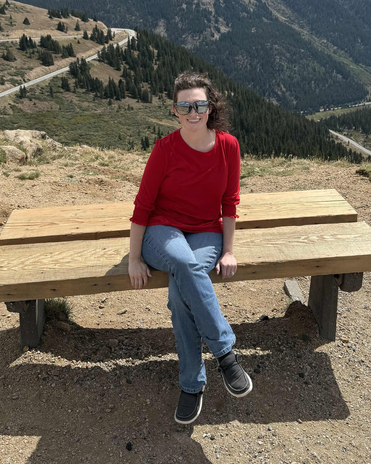 Maddie sitting on a bench at a mountain overlook