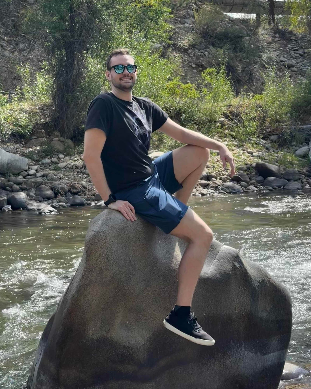 Seth sitting on a boulder in a mountain creek