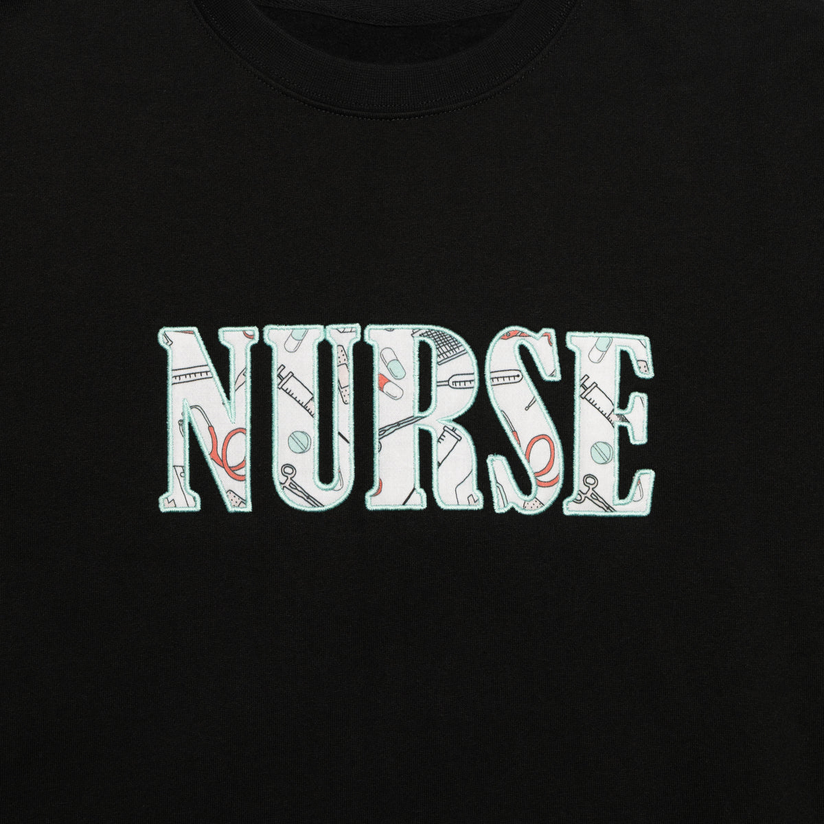 Close-up of the Nurse design appliqued on the chest of the Black crewneck