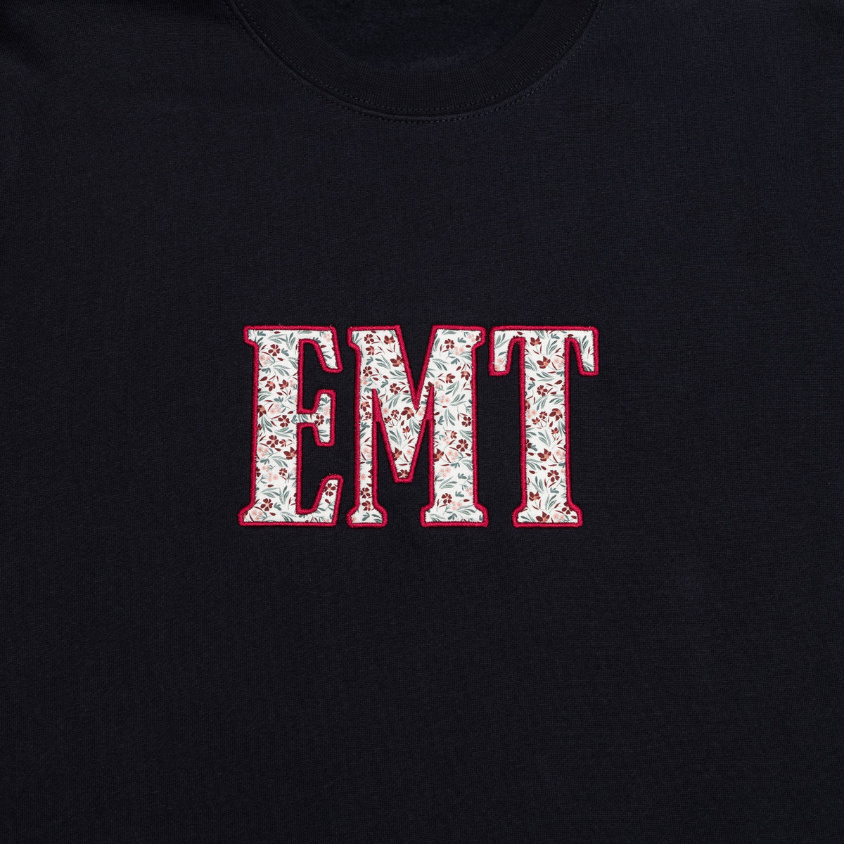 Close-up of the EMT design appliqued on the chest of the Classic Navy crewneck