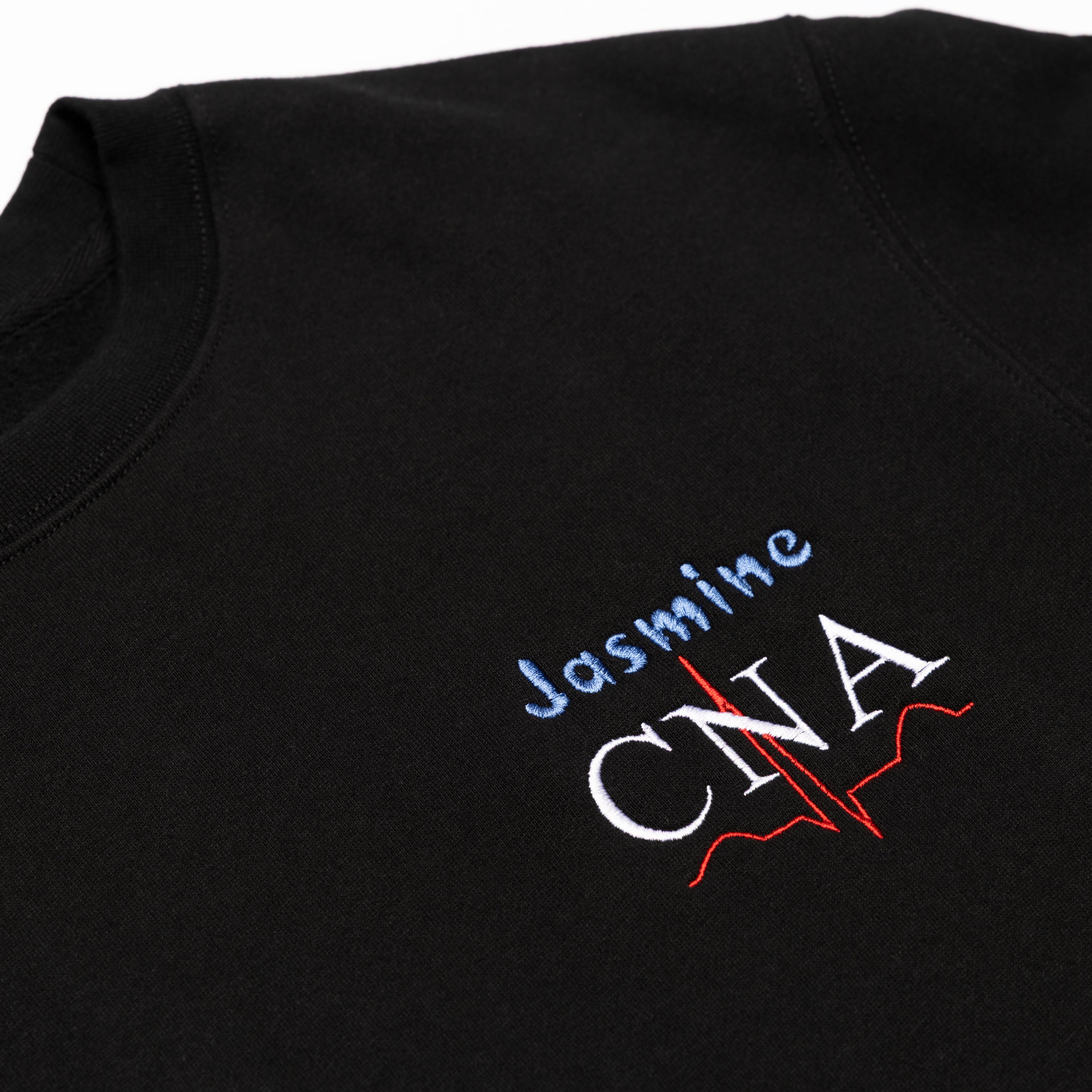 Close-up of a custom name and the CNA design embroidered on the chest of the Black crewneck
