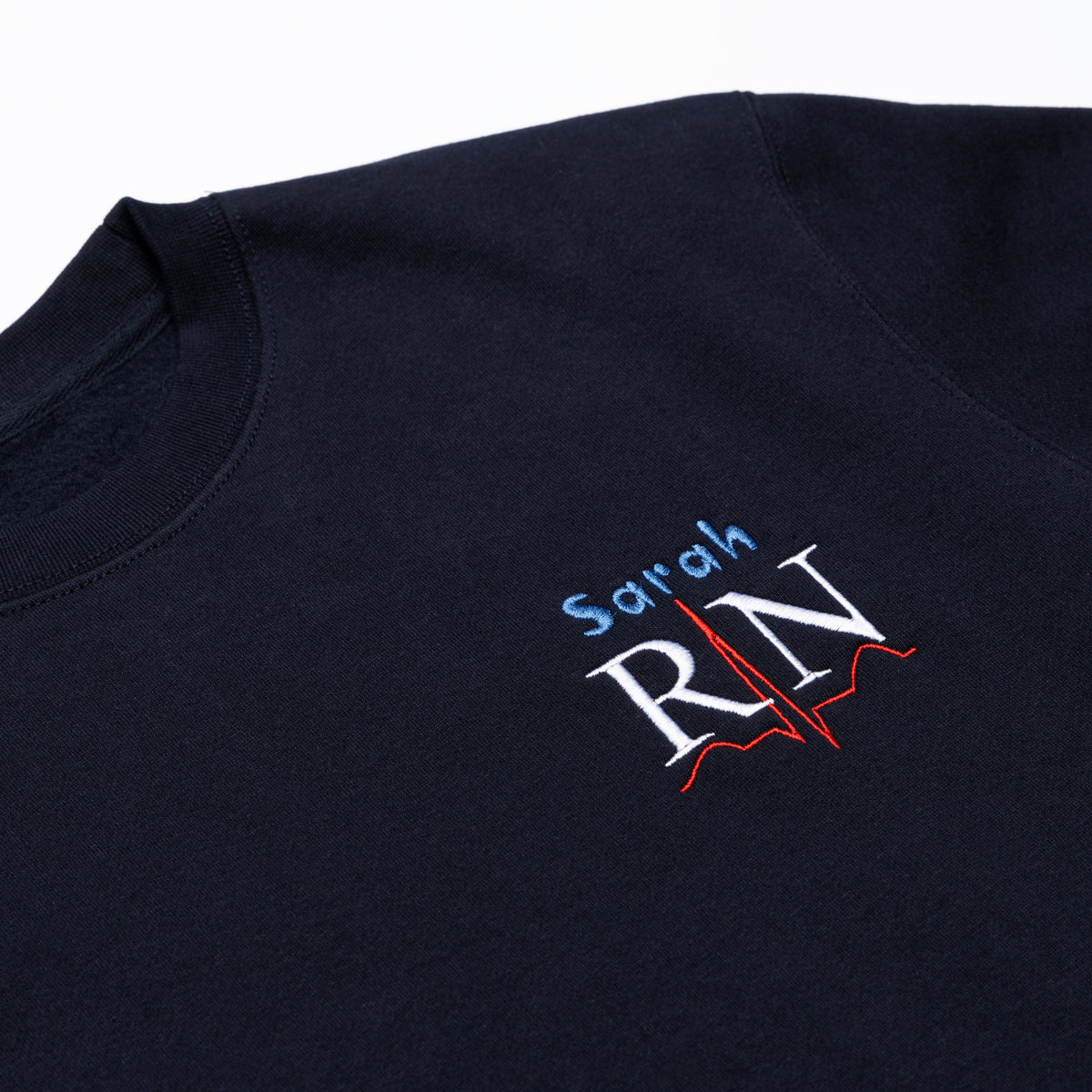 Close-up of a custom name and the RN design embroidered on the chest of the Classic Navy crewneck