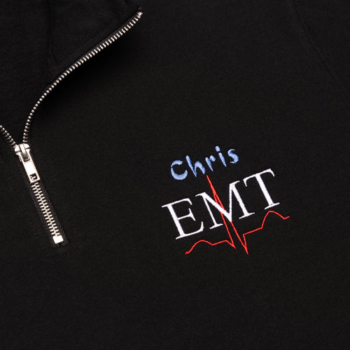 Close-up of a custom name and the EMT design embroidered on the chest of the Black quarter-zip